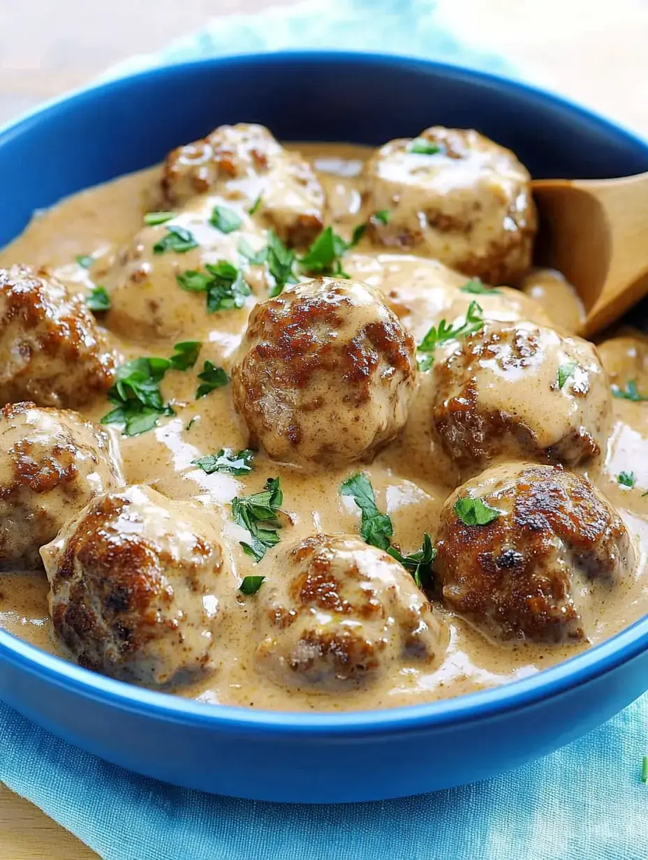 Un bol de délicieuses boulettes servies dans une sauce crémeuse, garnies de persil frais.