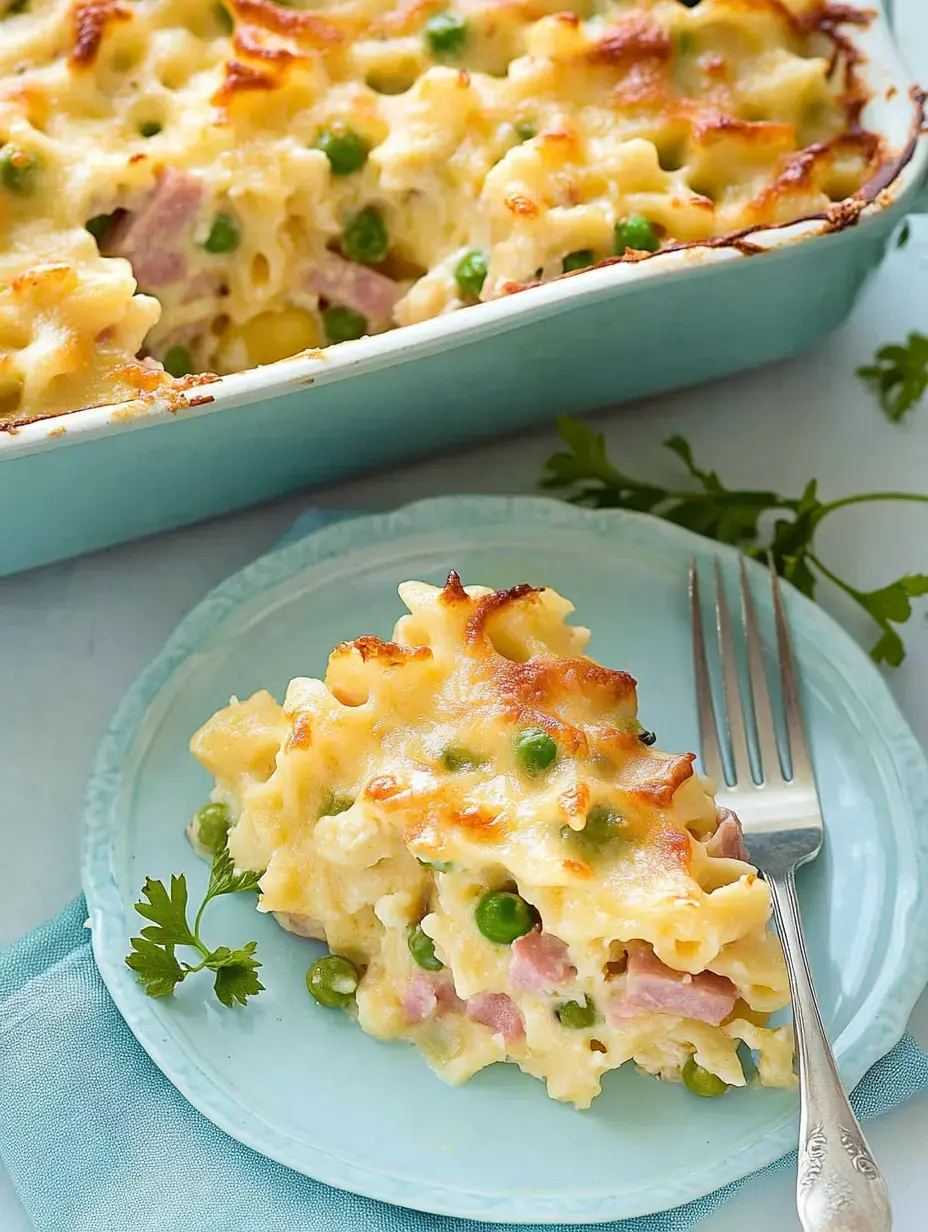 Une portion de gratin avec petits pois et jambon sur une assiette bleue, à côté d'un plat à gratin.