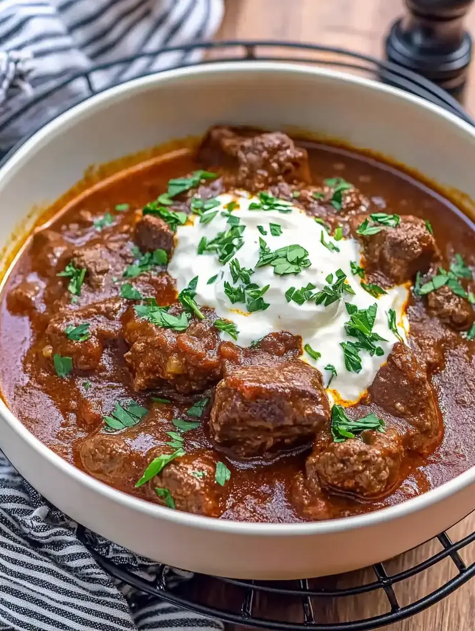 Une assiette de plat de viande épicé, garni d'herbes fraîches et d'une portion de crème aigre.