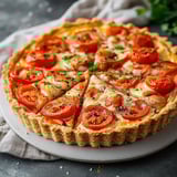 Une quiche aux tomates présentée sur un plateau rustique.