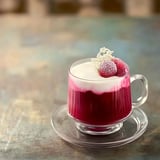 A glass of red liquid with a white topping.