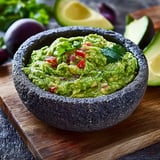 A bowl of guacamole with a spoon in it.
