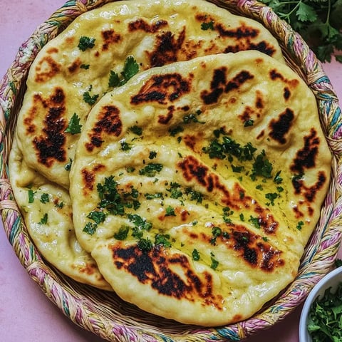 Un panier rempli de naans frais garnis de ciboulette avec de légères marques de cuisson.